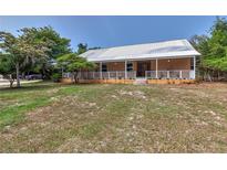 Charming single-story home with a metal roof, inviting front porch, and well-maintained lawn at 15625 Olney Ln, Spring Hill, FL 34610