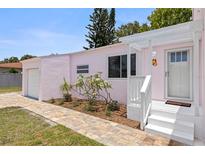 Charming pink home featuring a well-manicured lawn, tiled walkway, and a welcoming front porch at 1579 Bayshore Blvd, Dunedin, FL 34698