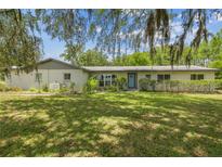 Charming single-story home with a well-manicured lawn, mature trees, and a welcoming blue front door at 2205 Henley Rd, Lutz, FL 33558