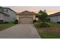 Charming single-story home featuring a brick driveway, two-car garage, and well-maintained landscaping at 30764 Lindentree Dr, Wesley Chapel, FL 33543