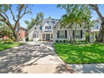 Charming white-brick home with mature trees, manicured lawn and long driveway at 3209 W Morrison Ave, Tampa, FL 33629