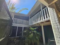 Exterior view of a two-story home featuring screened in balconies and a landscaped courtyard at 32348 Marchmont Cir, Dade City, FL 33523