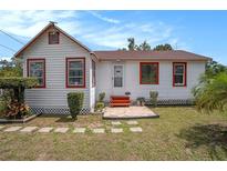 Charming home showcasing a white exterior with red trim and a well-maintained front lawn at 3405 E Diana St, Tampa, FL 33610