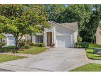 Charming single-story home with a well-manicured lawn, mature tree, and attached garage at 3512 Tealwood Cir, Palm Harbor, FL 34685