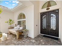 Elegant home front entrance featuring a decorative wrought iron door and an inviting seating area with stylish decor at 703 Monte Cristo Blvd, Tierra Verde, FL 33715