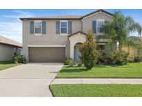 Two-story home featuring a two-car garage, manicured lawn, and tropical landscaping at 7170 Samuel Ivy Dr, Tampa, FL 33619