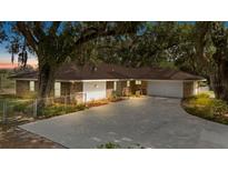 Beautiful exterior of a brick home featuring a manicured lawn and a long driveway leading to an attached garage at 9542 Wallien Dr, Brooksville, FL 34601