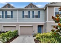 Charming townhome featuring a front-entry garage, stylish blue shutters, and a welcoming front door at 10907 Golden Acorn Ave, Tampa, FL 33610