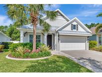Charming home showcasing lush landscaping, a well-manicured lawn, and a gray metal roof at 11510 Quiet Forest Dr, Tampa, FL 33635