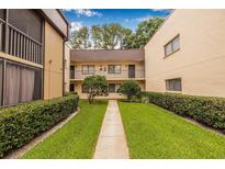 Exterior courtyard view of condo building with manicured bushes and sidewalk at 11816 Raintree Lake Ln # B, Tampa, FL 33617