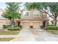 Two-story tan home featuring a well-manicured lawn, two-car garage, and charming stone accents at 11839 Castine St, New Port Richey, FL 34654