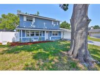 Charming two-story home featuring a manicured lawn, fresh mulch and bright blue siding at 12468 Empire Dr, Seminole, FL 33772