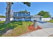 Charming two-story home with a blue exterior, well-maintained landscaping, and a spacious two-car garage at 12468 Empire Dr, Seminole, FL 33772