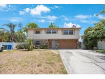 Two-story home with stone accents, a two-car garage, and a spacious front yard under a bright blue sky at 12803 126Th Ter, Largo, FL 33774
