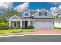 Charming two-story home with a well-manicured lawn, brick driveway, and a welcoming front porch with rocking chairs at 152 Glenn Moor Cir, Dunedin, FL 34698