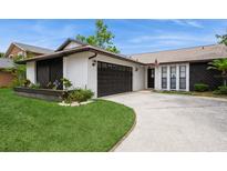 Charming single-story home featuring stucco siding, a dark two-car garage, and well-manicured landscaping at 15801 Cottontail Pl, Tampa, FL 33624