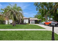 Charming single-story home featuring a lush green lawn, a mature palm tree, and a neatly paved driveway at 15801 Cottontail Pl, Tampa, FL 33624