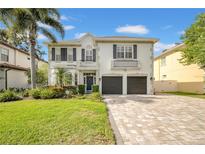Elegant two-story home with a well-manicured lawn, brick driveway, and inviting curb appeal at 3903 W De Leon St, Tampa, FL 33609
