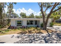 Charming single-story home with a well-manicured front yard, blue shutters and lush landscaping at 5270 Miller Bayou Dr, Port Richey, FL 34668
