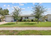 Charming single-story home boasts a well-manicured lawn, lush landscaping, and a welcoming facade under a bright, cloudy sky at 5961 41St N Ave, St Petersburg, FL 33709