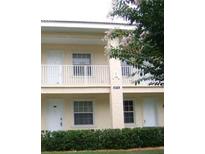 Beige two-story condo building featuring white doors, a balcony, and manicured shrubbery at 6714 Dali Ave # 102, Land O Lakes, FL 34637