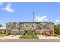Tan townhomes with garages and a red car parked in front on a sunny day at 6924 Towne Lake Rd, Riverview, FL 33578