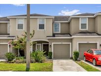 Close up of tan townhomes with garages and a red car parked in front at 6924 Towne Lake Rd, Riverview, FL 33578