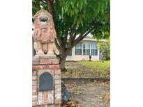 Home exterior featuring a brick mailbox with lion statue and large tree at 72 Lake Shore Dr, Palm Harbor, FL 34684