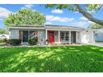 Charming single-story home featuring a well-manicured lawn, a bright red front door, and tasteful landscaping at 12401 Yorktown Ln, Bayonet Point, FL 34667