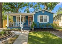 Charming blue single-story home featuring a cozy front porch, landscaped yard, and a quaint walkway at 1302 E Flora St, Tampa, FL 33604