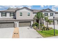 Charming two-story townhome featuring attached garages and beautifully landscaped front yard at 1396 White Fox Run, Lutz, FL 33549