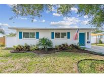 Charming single-story home features bright blue shutters and a neatly landscaped front yard with an American flag at 1529 Essex N Dr, St Petersburg, FL 33710