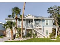 Charming two-story coastal home with a light blue exterior, complemented by palm trees and a well-manicured lawn at 216 High St, Tarpon Springs, FL 34689