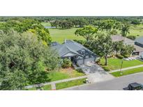Well-manicured home featuring lush landscaping, a two-car garage, and a serene setting overlooking a golf course at 2216 Eagle Bluff Dr, Valrico, FL 33596