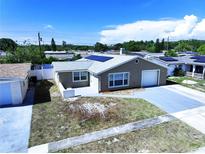 Attractive single-story home with solar panels, an attached garage, and a well-maintained lawn on a sunny day at 5139 Victoria Ln, Holiday, FL 34690