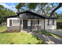 Charming single-story home featuring black and white exterior paint, brick accents, and well-manicured lawn at 5405 S Sellas St, Tampa, FL 33611