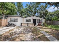 Charming single-story home with white exterior, black trim, mature trees, and motorcycle parked near driveway at 5801 92Nd N Ave, Pinellas Park, FL 33782