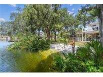 Stunning waterfront property with lush landscaping, sandy beach area, and calm waters for serene lakeside living at 7300 Mackerel Ln, Hudson, FL 34667