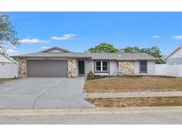 Charming single-story home featuring a well-maintained lawn, stone accents, and an attached garage at 8010 Chickasaw Ln, Port Richey, FL 34668