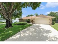 Charming single Gathering home with stone accents, a large driveway, mature trees, and a well maintained lawn at 8105 Valley Stream Ln, Hudson, FL 34667