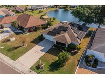 Aerial view of single-Gathering home with solar panels, well-manicured lawn, and waterfront access at 913 El Rancho Dr, Sun City Center, FL 33573