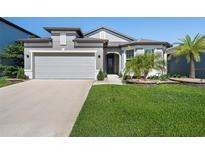 Charming single-Gathering home with well-manicured lawn, a gray stucco finish, and a spacious two-car garage at 9271 Rally Spring Loop, Wesley Chapel, FL 33545