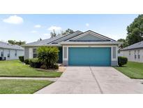 Charming single-story home featuring a vibrant blue garage door and well-manicured landscaping at 11845 Autumn Creek Dr, Riverview, FL 33569