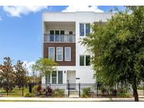 Modern three-story townhome featuring white exterior, dark trim, and a black metal fence at 121 E Warren Ave # 4, Tampa, FL 33602