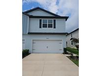 Charming two-story home with a white garage door and light blue siding at 19643 Shady Oak Dr, Land O Lakes, FL 34638