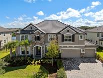 Stately two-story home featuring a stone facade, manicured lawn, paver driveway and a three-car garage at 33255 Kateland Dr, Wesley Chapel, FL 33545