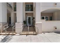 Inviting building entrance featuring bright stucco, steps, and minimalist hand railings leading to a glass door at 450 Knights Run Ave # 104, Tampa, FL 33602