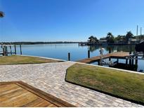 Beautiful waterfront backyard with well-maintained lawn, wooden dock, and gorgeous water views at 861 180Th E Ave, Redington Shores, FL 33708