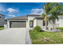 Charming single-story home featuring a gray two-car garage, well-manicured lawn, and stylish landscaping at 8812 Parsons Hill Blvd, Wesley Chapel, FL 33545