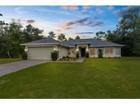 Charming single-story home featuring a well-manicured lawn, beautiful landscaping, and an attached two-car garage at 10197 Meadow Wren Ave, Weeki Wachee, FL 34613